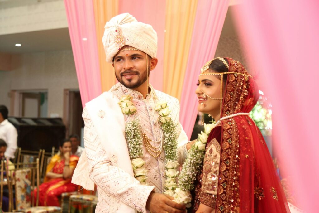 Indian bride and groom in traditional attire exchanging garlands during their wedding.