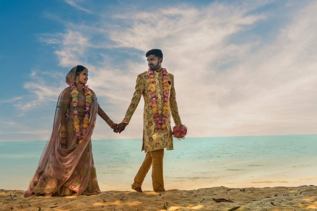 Couple celebrating their Indian destination wedding on a sunny beach.